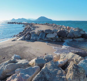 Felsiger Küstenweg bei Izmir mit Blick aufs Meer und entfernte Berge.