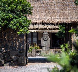 Traditionelles Haus mit Steinstatue auf Jeju in S&uuml;dkorea.