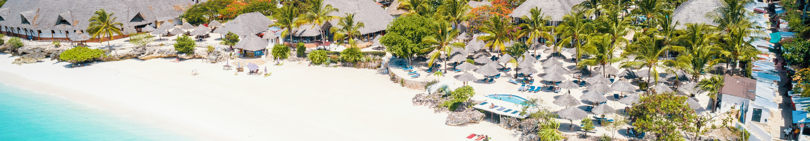Luftaufnahme von Nungwi Beach auf Sansibar, Tansania, mit wei&szlig;em Sandstrand, t&uuml;rkisfarbenem Meer, Palmen und traditionellen Strohdachh&uuml;tten entlang der K&uuml;ste.