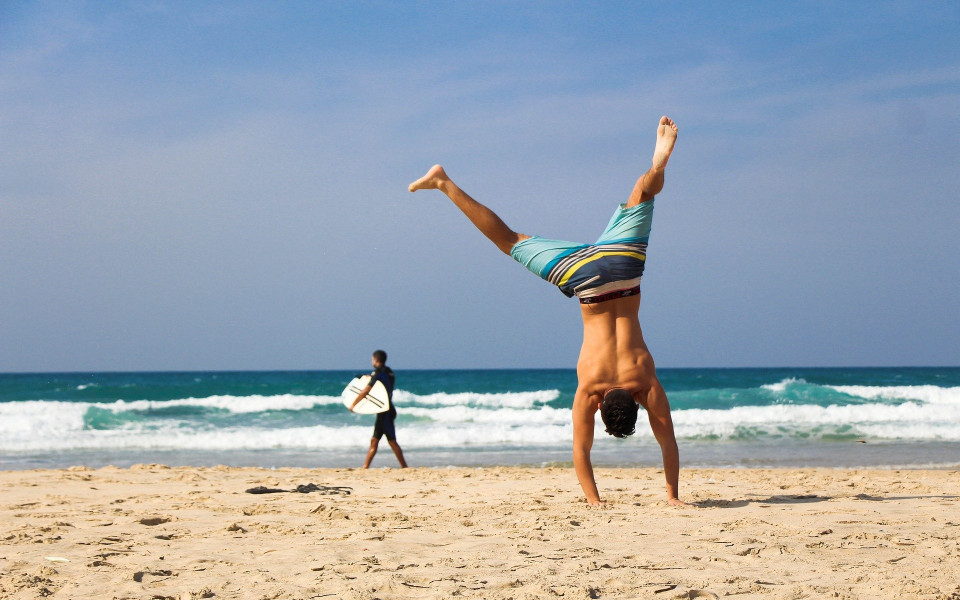 Mann macht Handstand am Strand
