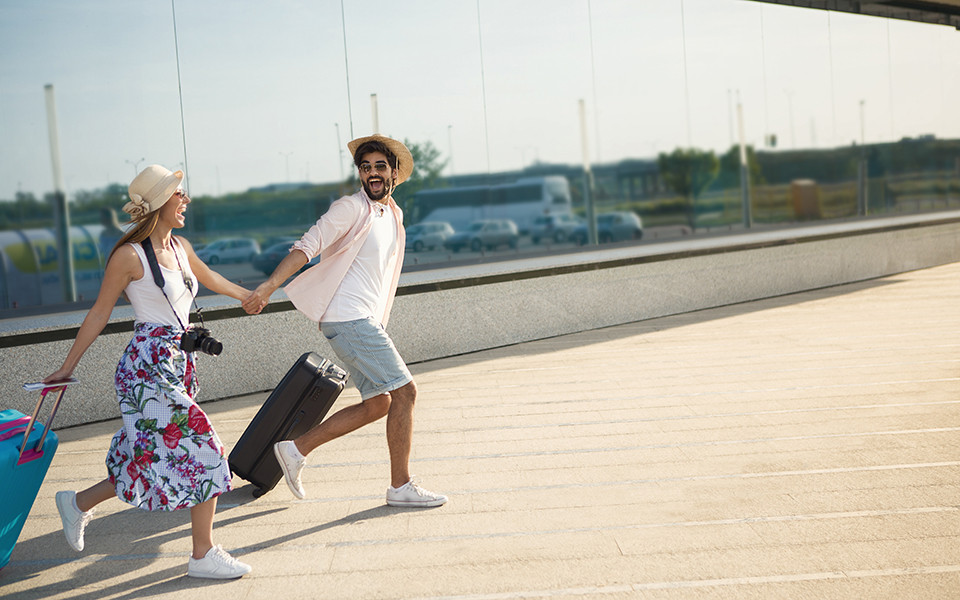 Last Minute Urlaub: Paar mit Koffer und Kamera