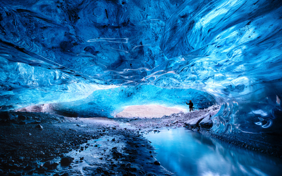 Mann macht ein Foto in der Öffnung einer Eishöhle im Vatnajökull-Gletscher im Südosten Islands