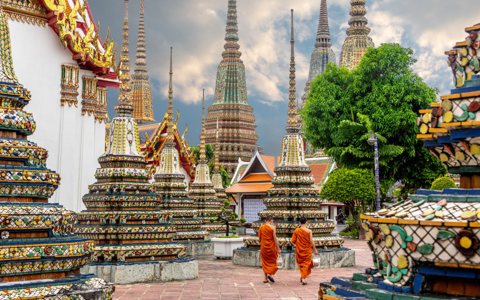 Zwei M&ouml;nche gehen an Stupas im Wat Pho Tempel in Bangkok entlang.